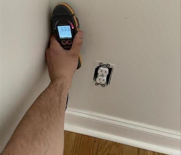 Technician holding a meter to the wall