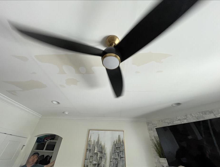 water damage on ceiling behind a ceiling fan.